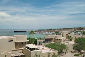 A coastal town with buildings, a marina, and a large ship in the distance.