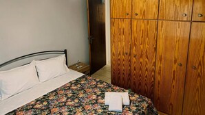 Een slaapkamer met een bed, een houten kledingkast en een hanglamp.