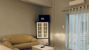 Een woonkamer met een bank, een tafeltje, een kast en een raam met gordijnen.