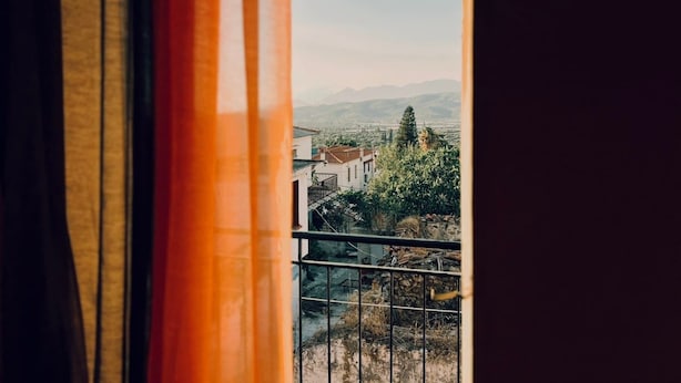 Ein Balkon mit Blick auf eine Stadtlandschaft und ferne Berge.