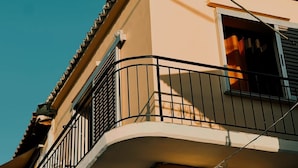 Ein Gebäude mit einem gebogenen Balkon, einem fenster mit Vorhängen und einem Ziegeldach.