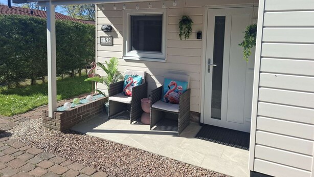 A covered porch with a seating area, a door, and a window.