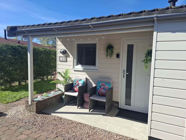 A covered porch with a seating area, a door, and a window.