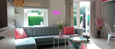 A modern living room with a grey sofa, a small round table, and a neon sign.