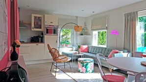 A modern living room with a sofa, chairs, a dining table, and a kitchen area with cabinets and appliances.