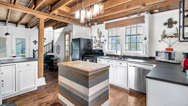 A modern kitchen with wooden beams, white cabinetry, and a central island.