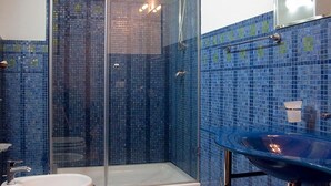 Une salle de bain avec une douche à parois de verre, un lavabo blanc et des murs recouverts de mosaïques bleues.