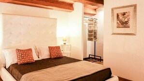 Une chambre à coucher avec un grand lit, un plafond en bois, une tête de lit blanche et un tableau encadré au mur.