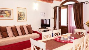 A cozy room with a sofa, a TV, a dining table with candles, and artwork on the wall. - Borgo degli Angeli Resort & Spa (Partinico)