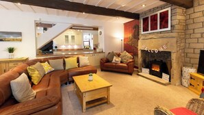 A cozy living room with a stone fireplace, leather sofas, and a wooden coffee table.