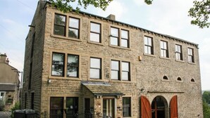 A two-story stone building with multiple windows and a central entrance with arched doors.
