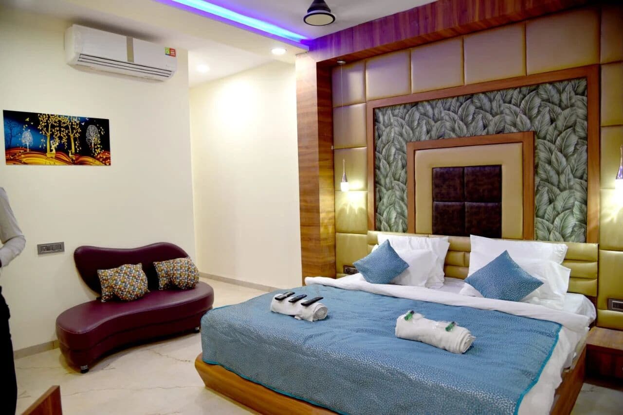 Een hotelkamer met een groot bed, een rode bank en een wandairconditioning.