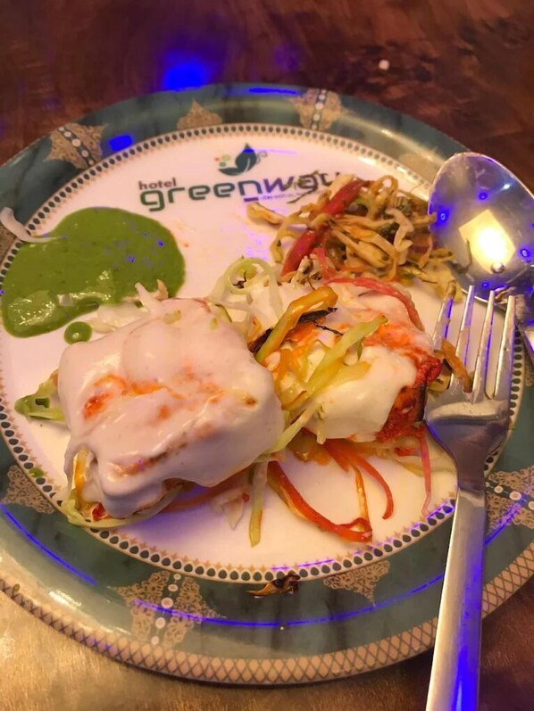 Un plato con salsa verde, salsa blanca, y un guiso de vegetales rallados con cobertura cremosa.