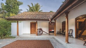 Une maison traditionnelle avec un toit en tuiles, une porte en bois et une véranda avec des chaises.