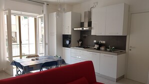 Una cucina funzionale con mobili bianchi, un tavolo da pranzo con sedie e un divano rosso.