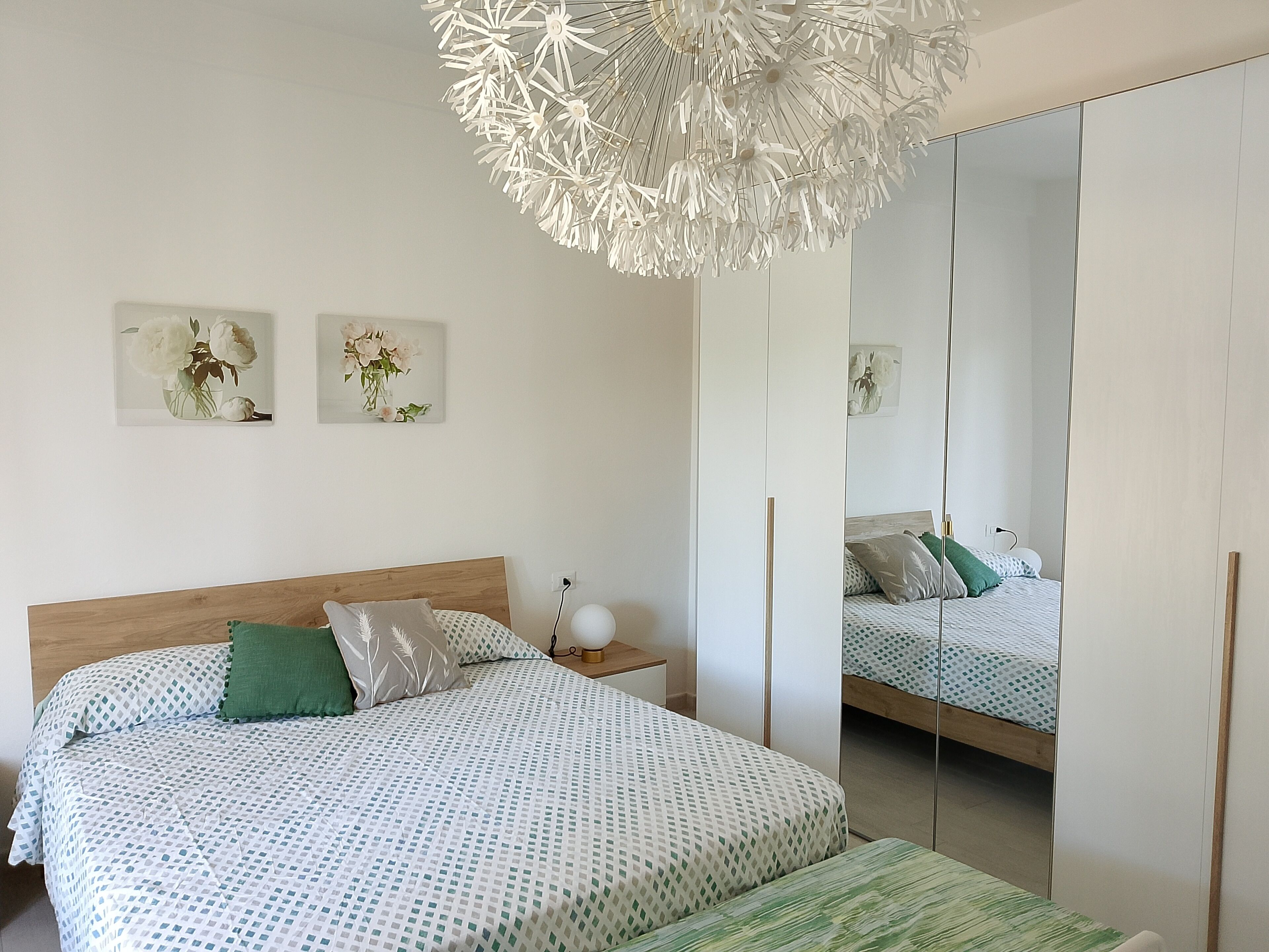 Ein Schlafzimmer mit Bett, Nachttisch und einem großen Spiegel.