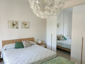 Une chambre à coucher comprenant un lit, une table de chevet, une commode et un grand miroir.