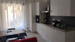 Una cucina moderna con mobili bianchi, un piano cottura a gas e un'area pranzo con tavolo e sedie.