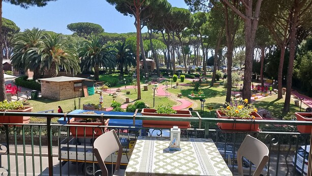 Una terrazza con posti a sedere all'aperto, vista su un giardino curato e un piccolo edificio sullo sfondo.