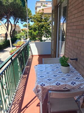 Un balcon avec une table, des chaises et un pot de fleurs.