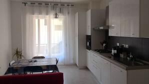Una cucina moderna con mobili bianchi, un piano di lavoro in acciaio inossidabile e un'area pranzo con tavolo e sedie.