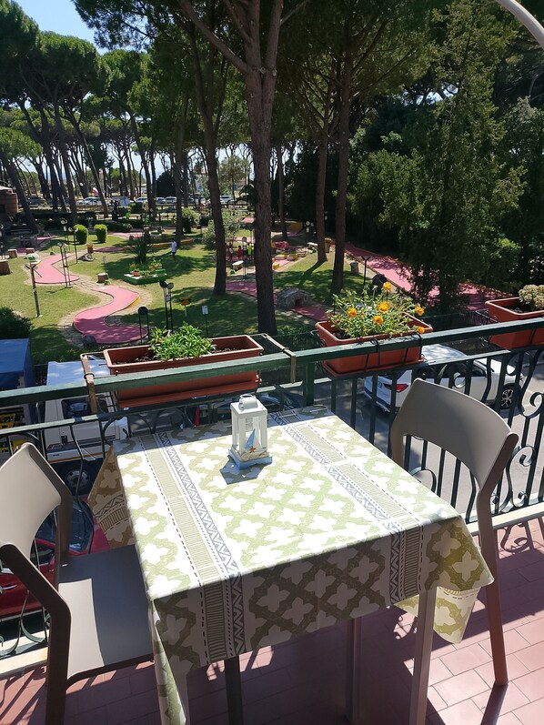 Un espace extérieur aménagé avec une table et des chaises, entouré de plantes en pot et d’arbres.
