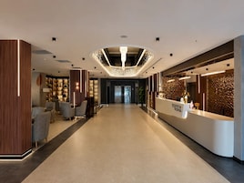 Un moderno vestíbulo de hotel con mostrador de recepción, área de descanso y techo decorativo.