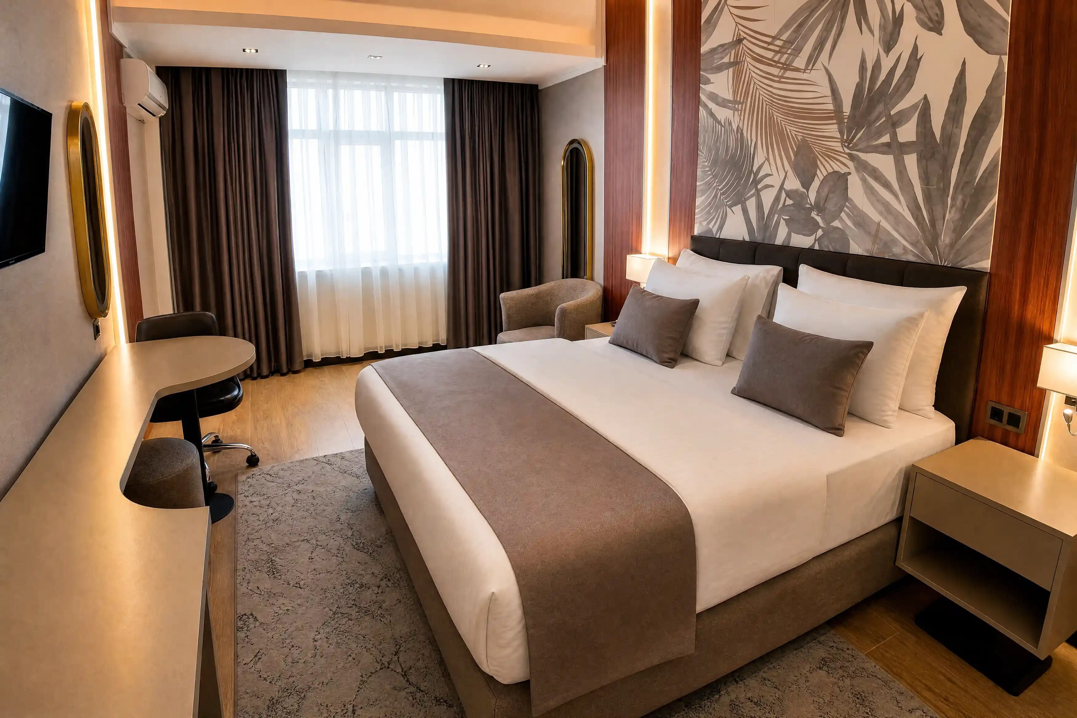 Una habitación de hotel con cama, mesita de noche, lámpara y escritorio con silla.
