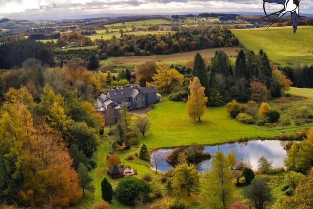 A large estate with multiple buildings, a pond, and surrounding trees.