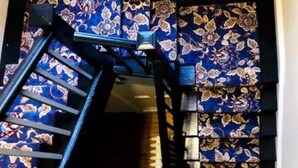 Eine Treppe mit blauem, floralem Teppich führt in einen dunklen Innenraum.