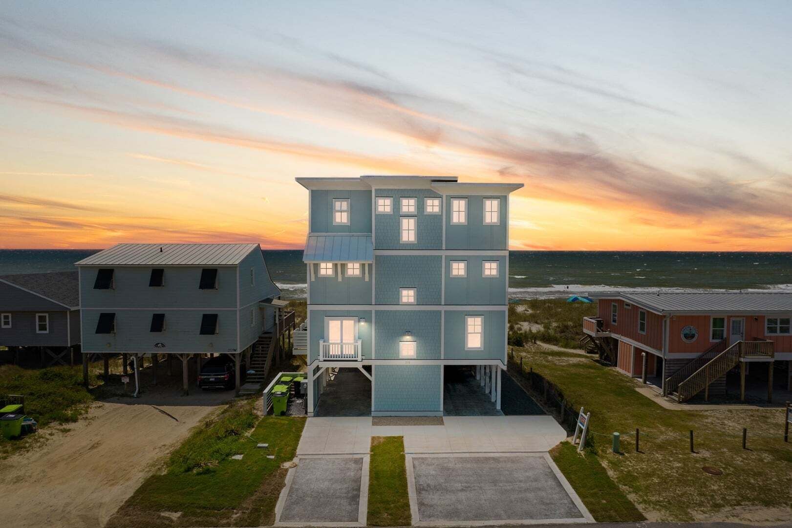 Een meerhoog gebouw met een balkon, gelegen nabij een strand met uitzicht op een zonsondergang.