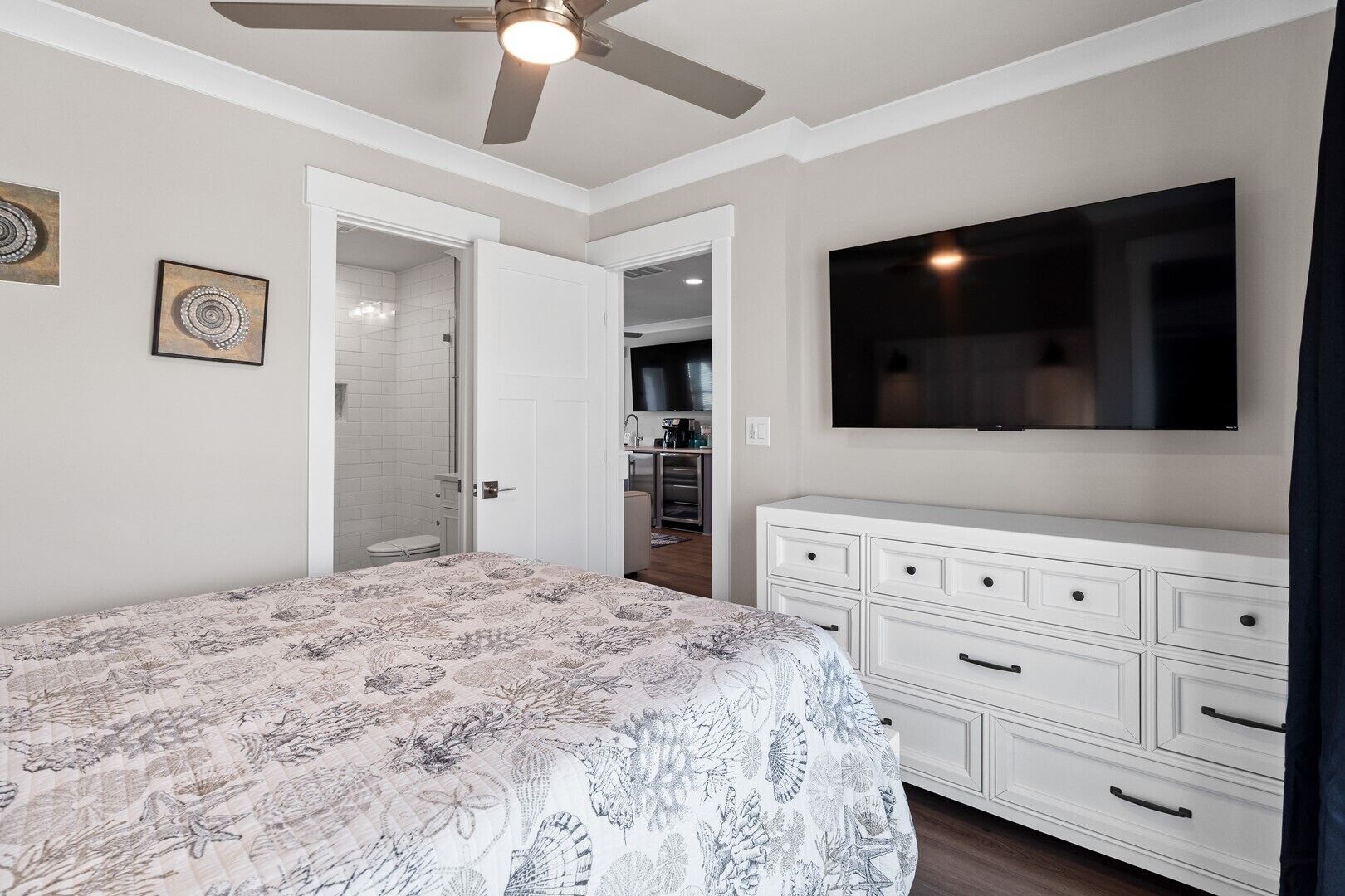 Ein Schlafzimmer mit Bett, Kommode, Fernseher und Deckenventilator.