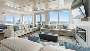 A spacious living area with a large sofa set, a fireplace, and a view of the ocean.
