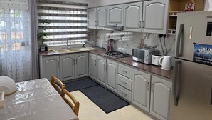 Una cocina moderna con armarios blancos, estufa integrada y refrigerador.