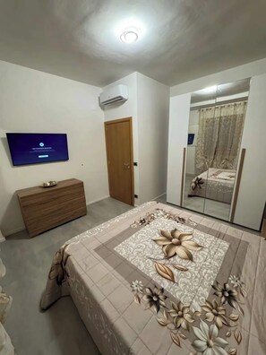 A bedroom with a bed, a dresser, a television, and a wardrobe.
