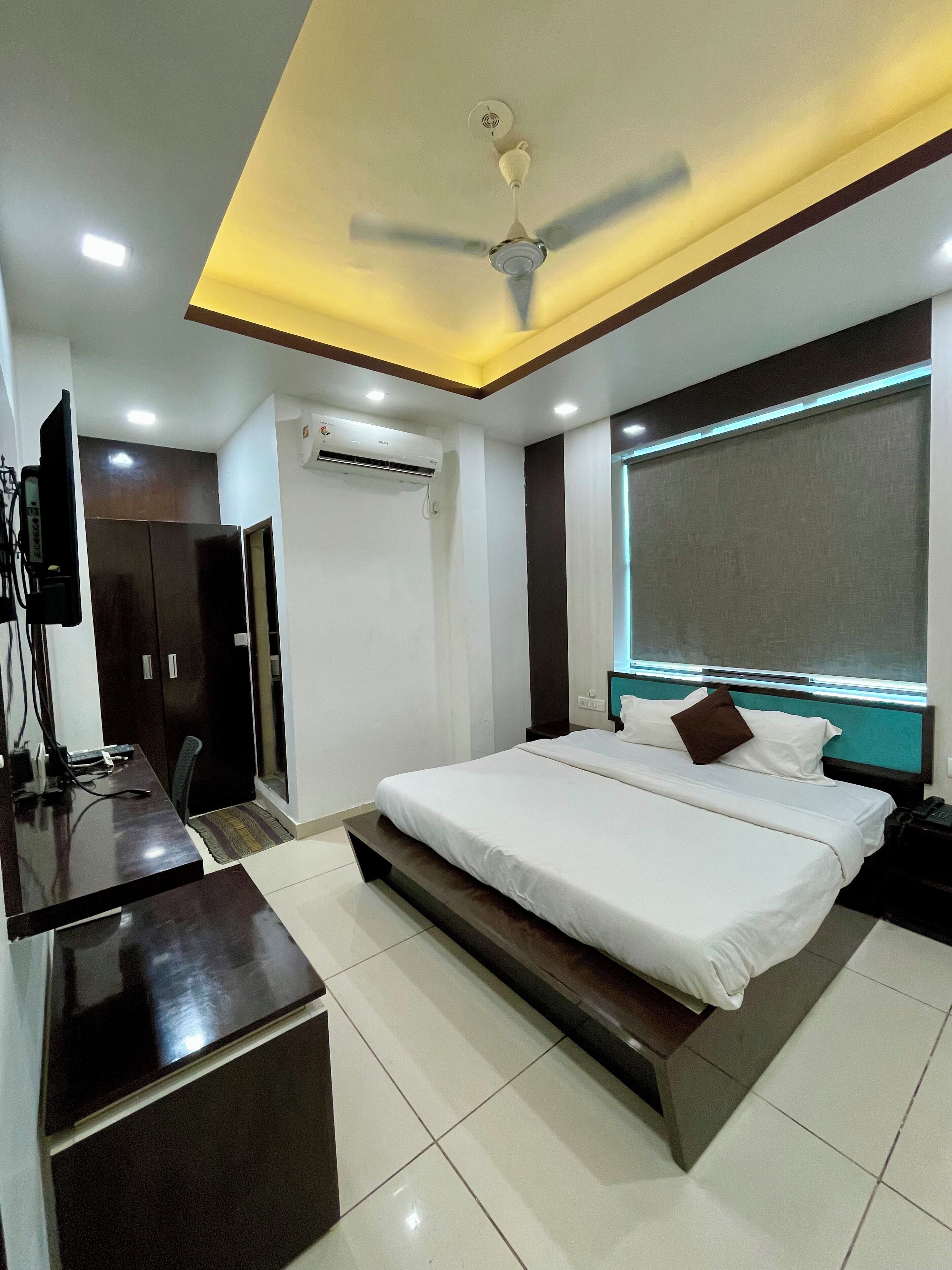 A modern bedroom with a bed, desk, and ceiling fan.