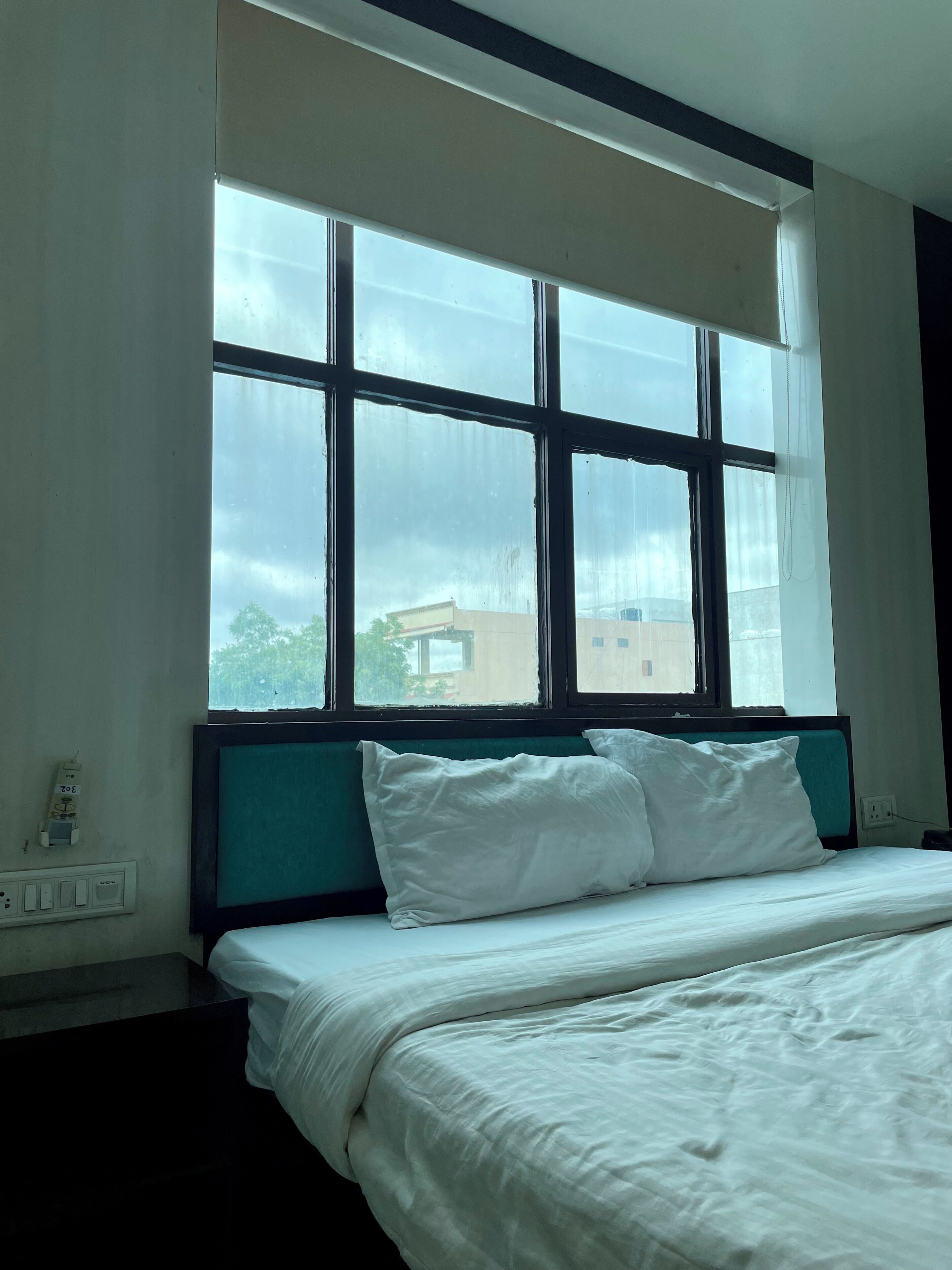 Une chambre d’hôtel avec un lit, une fenêtre et une prise électrique au mur.