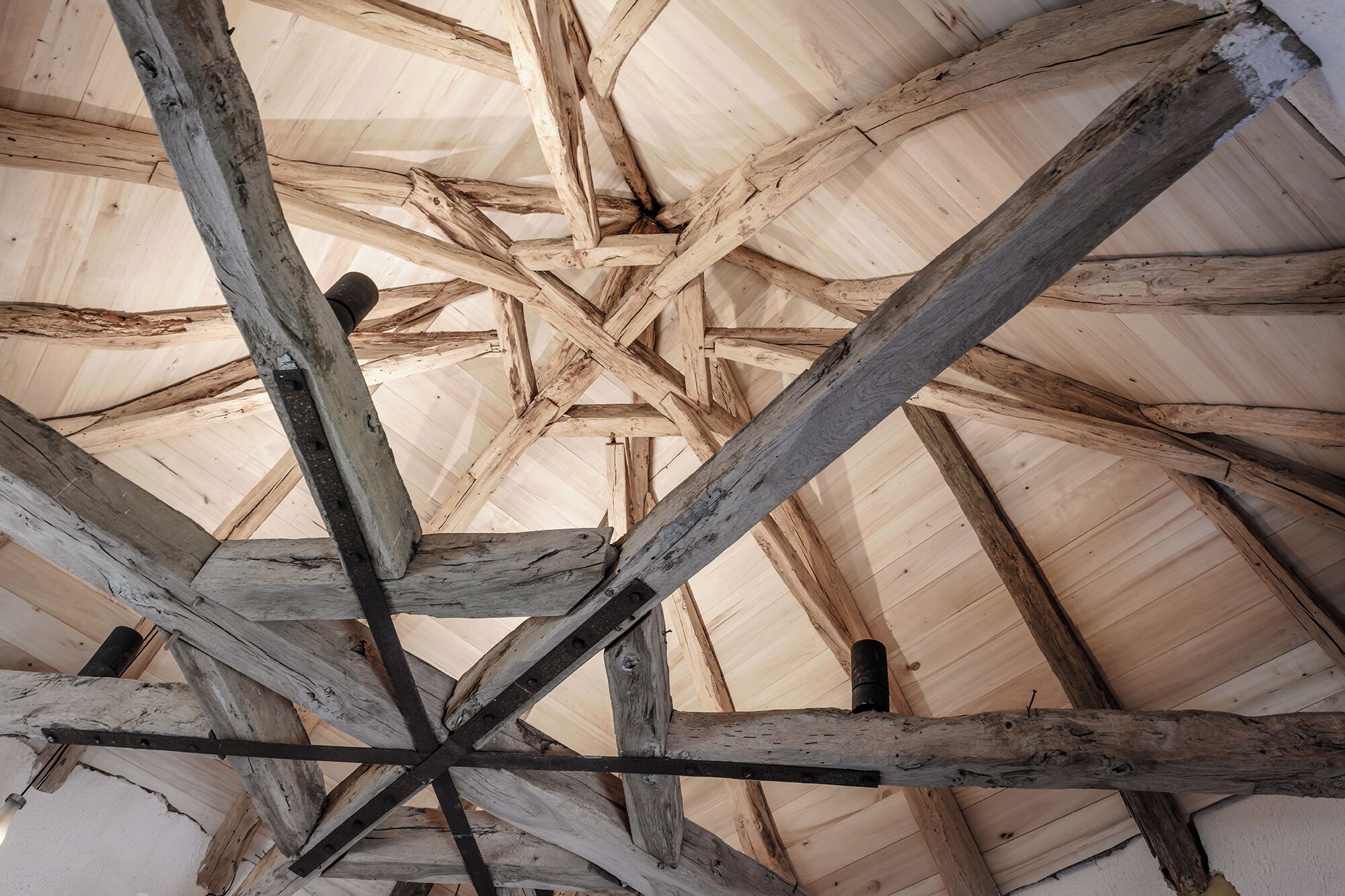 Une structure de plafond en bois composée de poutres qui se croisent.