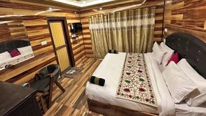 Habitación de hotel con pared de paneles de madera, cama con ropa blanca, escritorio y una silla, y un espejo.