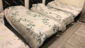 A room with three beds, each with a floral bedspread and black headboards.