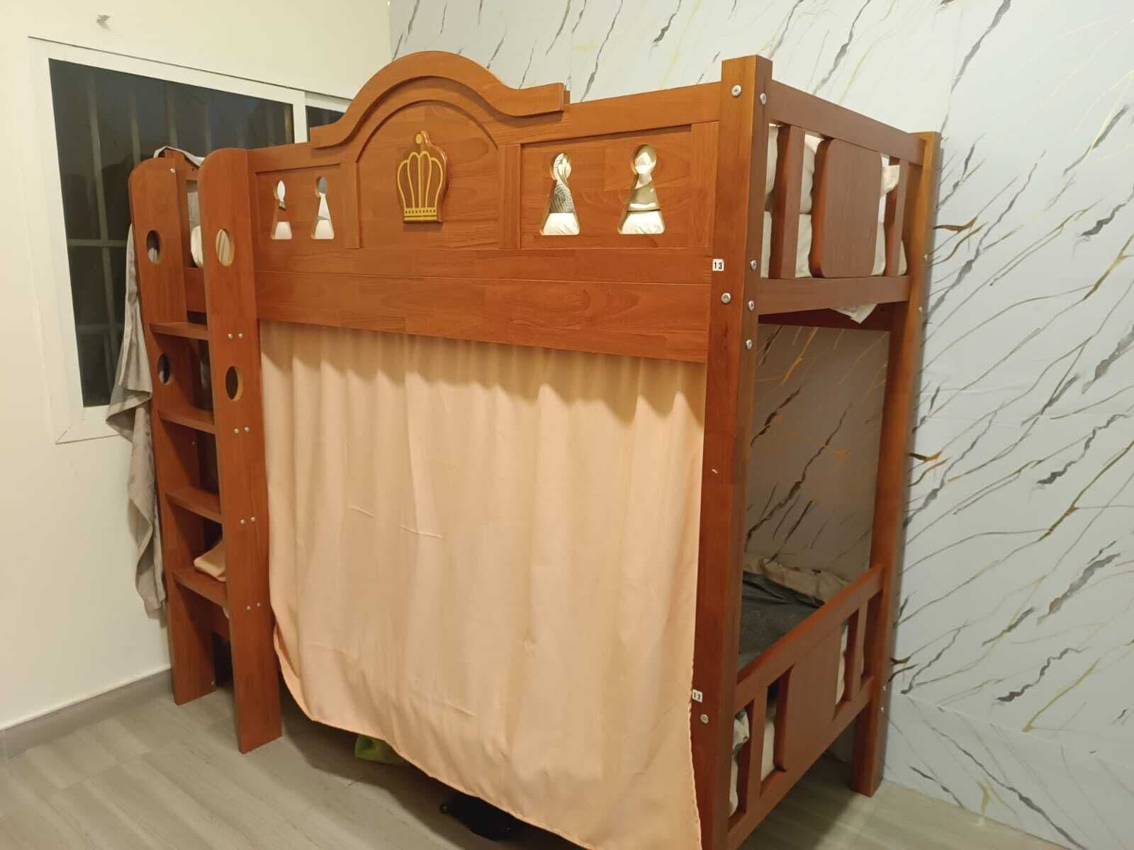 A wooden bunk bed with a canopy, a ladder, and a headboard with decorative elements.