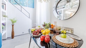 Comedor con mesa de vidrio, fruta y un espejo en la pared.