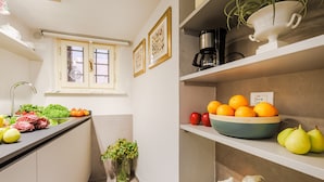 A kitchen with a sink, a window, and a bowl of fruit on the counter. - The Atelier House Lucca (Lucca)