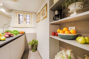 Una cocina con un lavamanos, una ventana y un bol de fruta en la encimera.