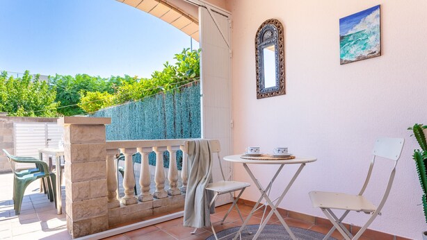 A balcony with a table and chairs, a decorative mirror, and a painting of the sea. - Casa Marquesa with barbecue, 15 min from the beach (L'Escala)