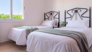 A bedroom with two beds, a window, and a plant. - Casa Marquesa with barbecue, 15 min from the beach (L'Escala)