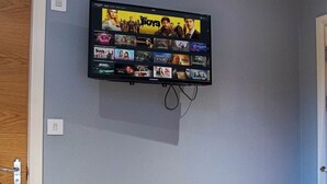 A television mounted on a wall displaying a selection of movies. - Spacious Ensuite 2-Bedroom Flat in Kelham Island (South Yorkshire)