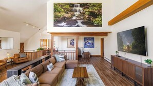 A spacious living room with a large wooden coffee table, a sofa set, and a TV on a wooden stand. - Designer Forest Cabin w/Hot Tub Near CherrySprings (Coudersport)