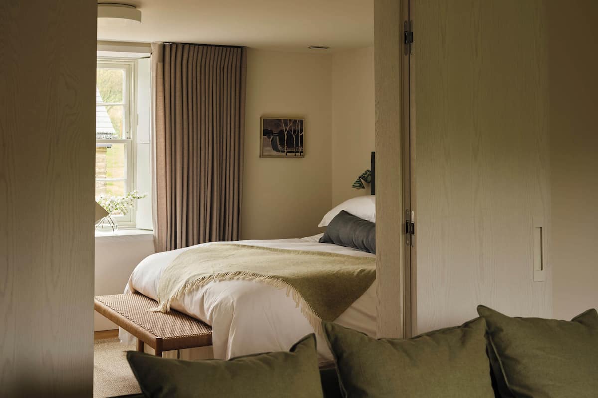 Ein Schlafzimmer mit einem Bett, einer Bank und einer Tür.