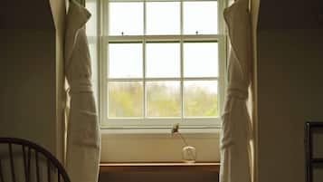 Una habitación con ventana, una silla y un taburete pequeño.